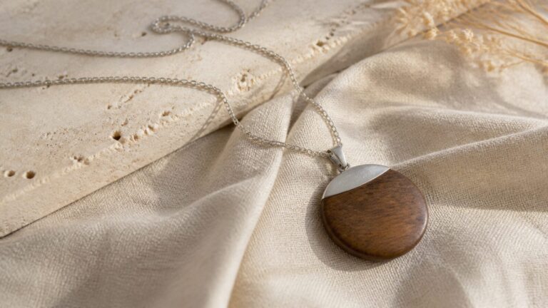 Wood and silver pendant arranged on linen and pale stone