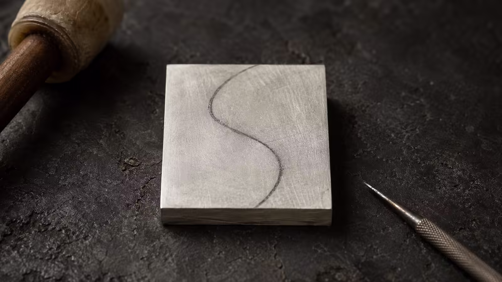 The Foundation of Form - Estovio 925 silver sheet with charcoal S-curve drafting line on a dark workbench
