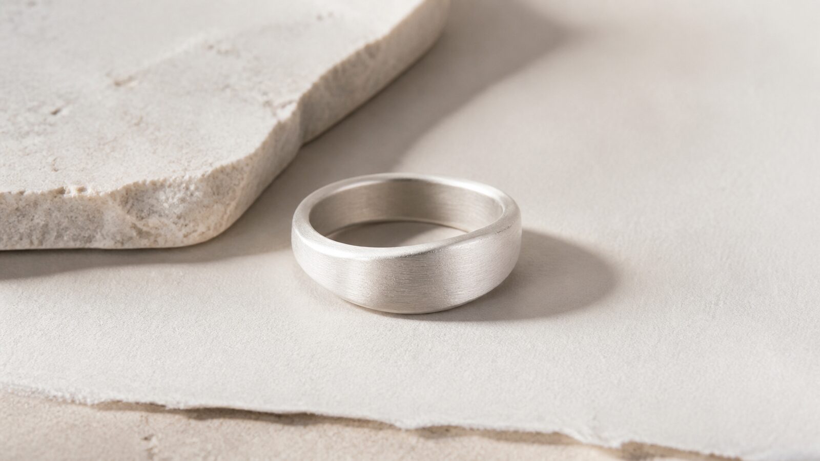 Matte silver ring on pale stone and handmade paper